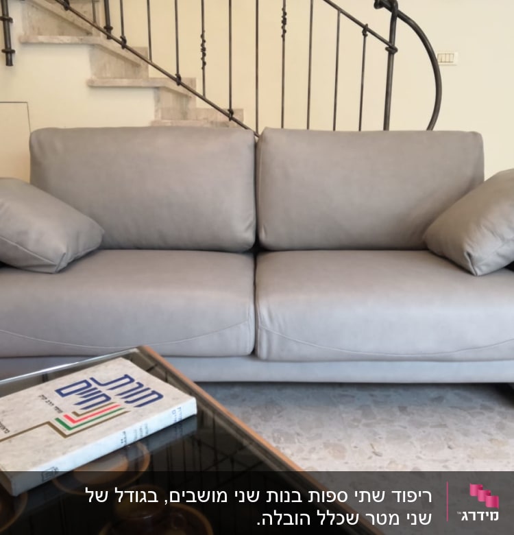 ספה אפורה עם כריות על שולחן זכוכית